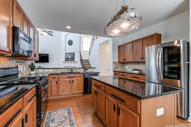 kitchen with ceiling fan, dark stone counters, backsplash, black appliances, and a center island