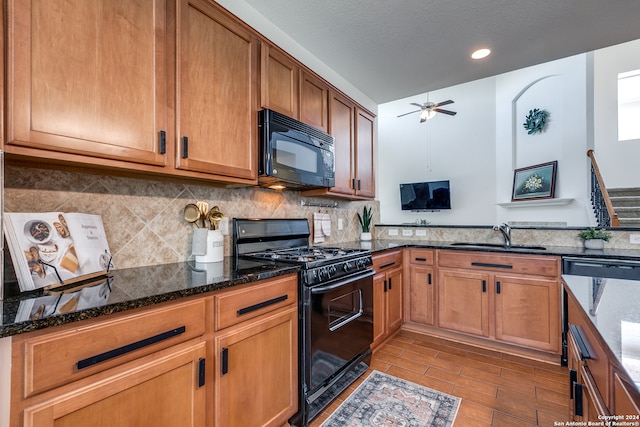 kitchen featuring dark stone counters, ceiling fan, black appliances, backsplash, and sink