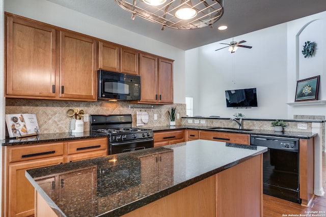 kitchen featuring ceiling fan, black appliances, sink, light wood-type flooring, and dark stone countertops