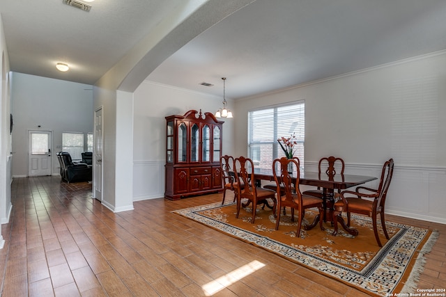 dining room with hardwood / wood-style floors, a notable chandelier, and crown molding