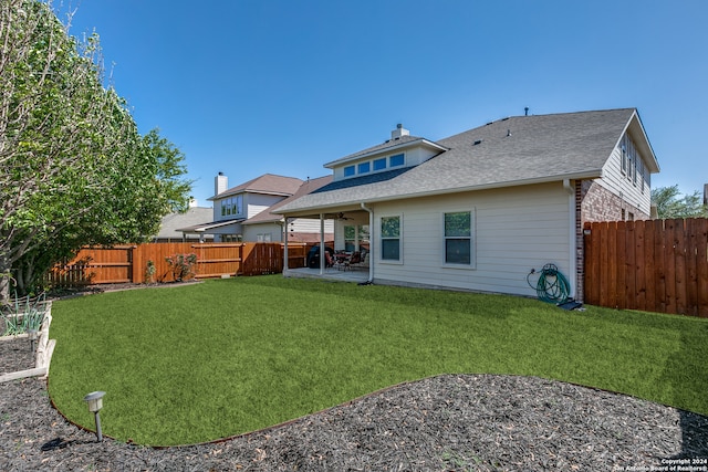 rear view of house featuring a lawn and a patio