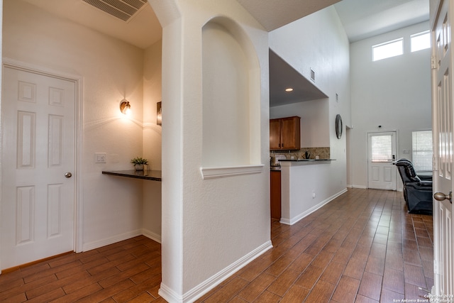 corridor with dark hardwood / wood-style flooring and a high ceiling