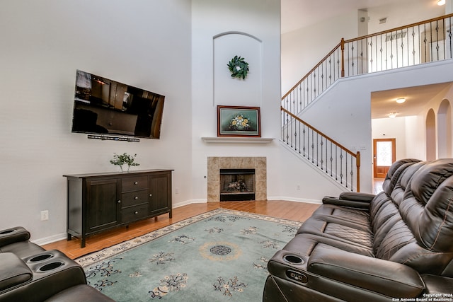 living room with light hardwood / wood-style floors, a towering ceiling, and a fireplace