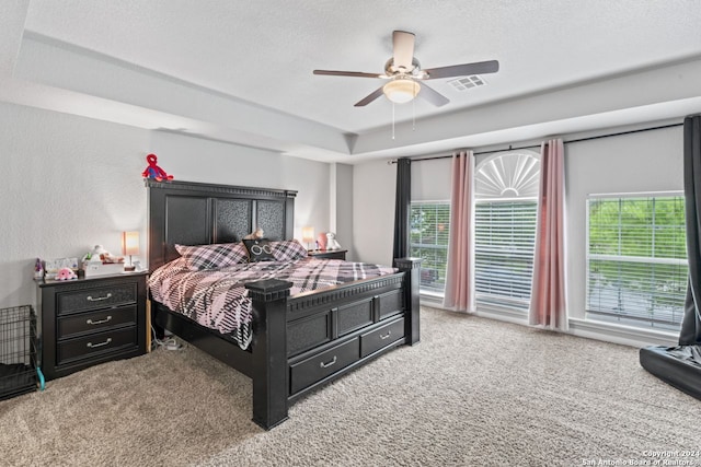 carpeted bedroom featuring ceiling fan, a textured ceiling, and a raised ceiling