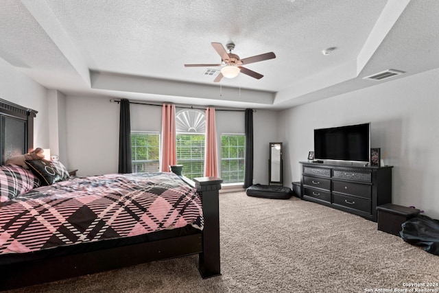 bedroom with ceiling fan, a textured ceiling, carpet floors, and a raised ceiling