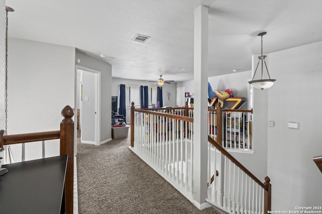 hall featuring dark carpet and a textured ceiling