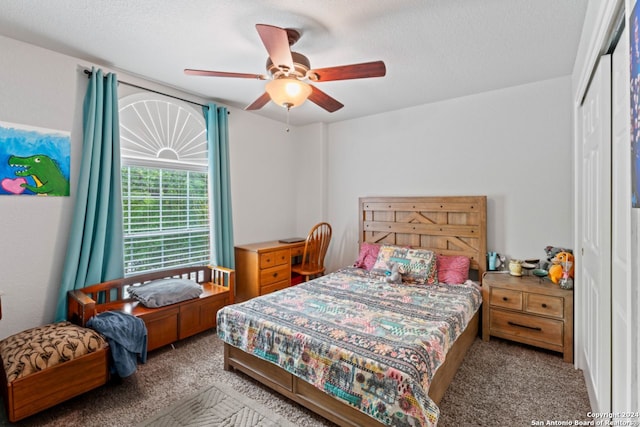 carpeted bedroom with a closet, ceiling fan, and a textured ceiling