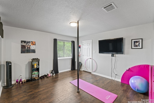 workout area with dark hardwood / wood-style flooring and a textured ceiling