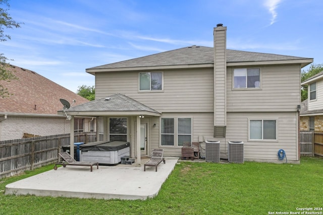 rear view of property with central AC, a hot tub, a lawn, and a patio