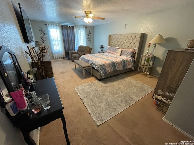 bedroom with ceiling fan, a textured ceiling, and light carpet