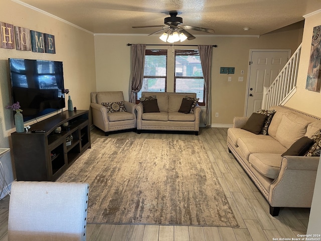 living room featuring ceiling fan, a textured ceiling, ornamental molding, and light wood-type flooring