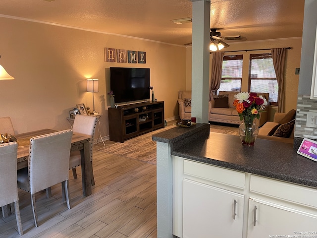 kitchen featuring ceiling fan, ornamental molding, a textured ceiling, white cabinetry, and light wood-type flooring