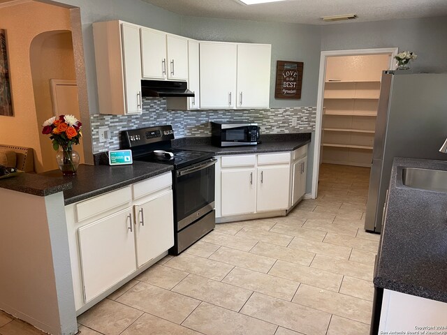 kitchen featuring white cabinets, backsplash, appliances with stainless steel finishes, and light tile flooring