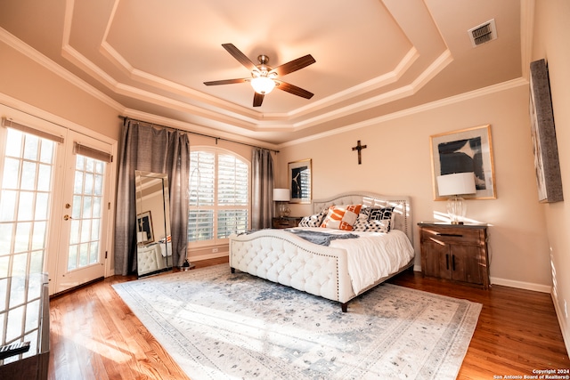 bedroom with french doors, ceiling fan, crown molding, a tray ceiling, and hardwood / wood-style flooring