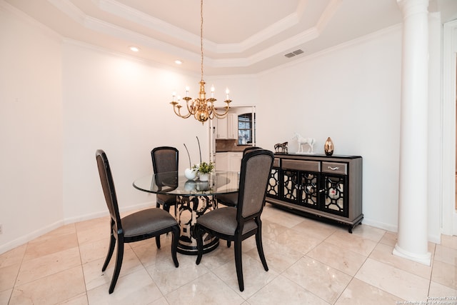 tiled dining area with a tray ceiling, ornamental molding, an inviting chandelier, and ornate columns