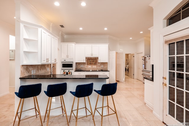 kitchen with dark stone counters, tasteful backsplash, light tile floors, white cabinetry, and oven