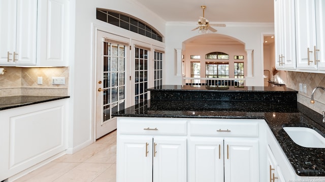 kitchen with dark stone countertops, white cabinets, and backsplash