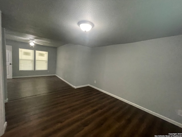 unfurnished room with dark hardwood / wood-style flooring, ceiling fan, and a textured ceiling