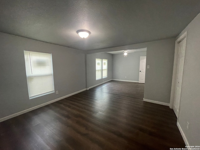 unfurnished room featuring ceiling fan, a textured ceiling, and dark wood-type flooring