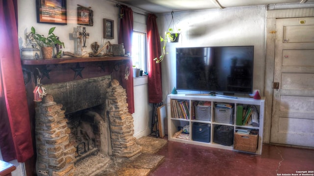 living area with a stone fireplace and finished concrete floors