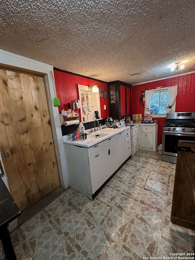 kitchen with stainless steel gas stove, stone finish floor, light countertops, and a textured ceiling