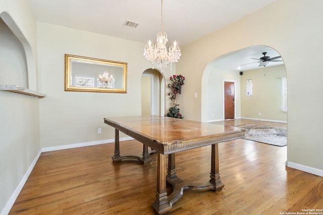 dining area featuring dark hardwood / wood-style flooring and ceiling fan with notable chandelier