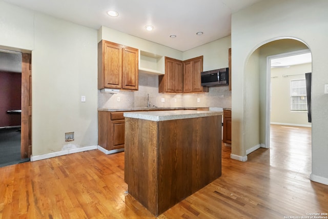 kitchen featuring backsplash, a center island, sink, and light hardwood / wood-style flooring