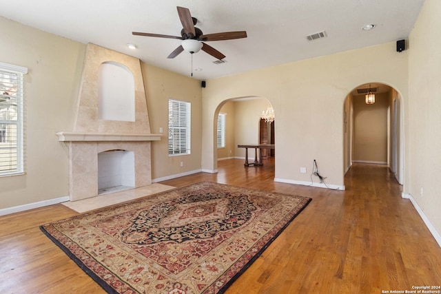 living room with ceiling fan, light wood-type flooring, and a large fireplace