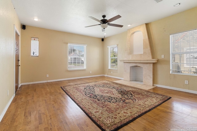 living room featuring a fireplace, ceiling fan, and light hardwood / wood-style flooring