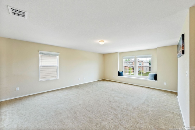 empty room featuring a textured ceiling and light colored carpet