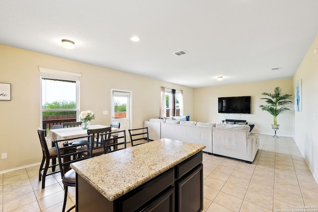 kitchen with plenty of natural light, a kitchen breakfast bar, light stone countertops, and a center island