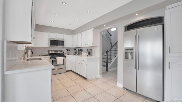 kitchen with backsplash, stainless steel appliances, white cabinetry, and light tile floors