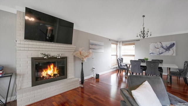 dining area with dark hardwood / wood-style floors, a notable chandelier, brick wall, a brick fireplace, and crown molding