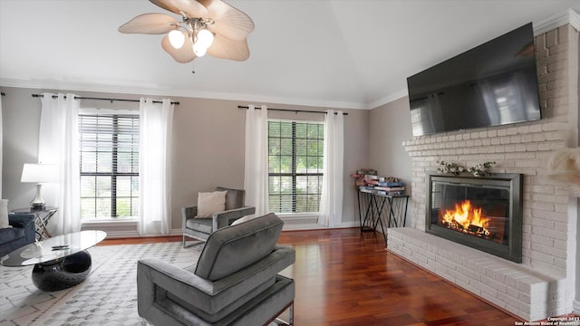 living room featuring ceiling fan, a fireplace, brick wall, dark hardwood / wood-style flooring, and ornamental molding