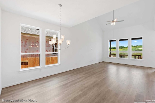 unfurnished dining area with wood-type flooring, ceiling fan with notable chandelier, and vaulted ceiling