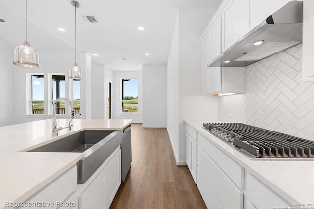 kitchen with appliances with stainless steel finishes, dark hardwood / wood-style floors, tasteful backsplash, wall chimney range hood, and white cabinets