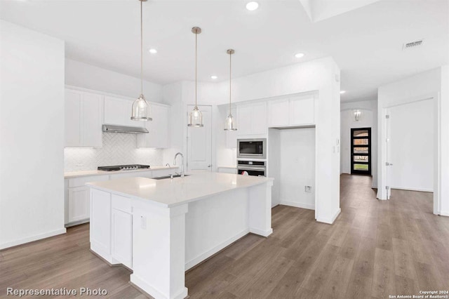 kitchen with an island with sink, white cabinets, sink, stainless steel appliances, and light hardwood / wood-style flooring