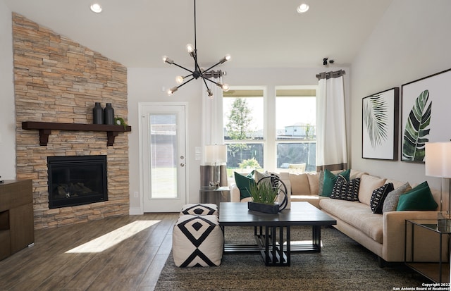 living room with a chandelier, a stone fireplace, vaulted ceiling, and dark wood-type flooring