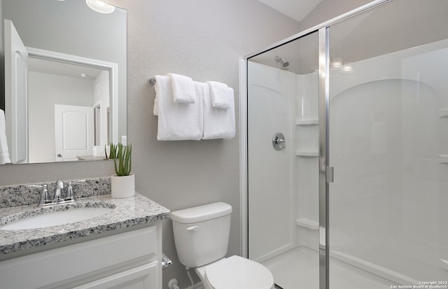 bathroom featuring a shower with shower door, oversized vanity, and toilet