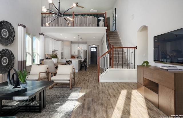 living room with light hardwood / wood-style flooring, a notable chandelier, and a towering ceiling