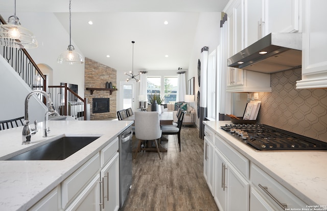 kitchen with dark hardwood / wood-style floors, a fireplace, wall chimney range hood, tasteful backsplash, and pendant lighting