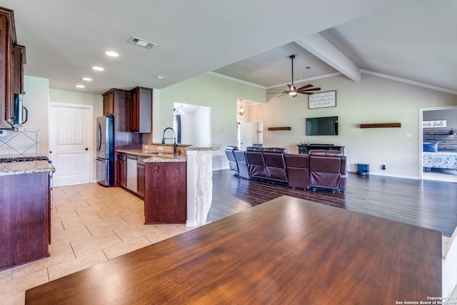 kitchen with stainless steel appliances, light stone countertops, ceiling fan, backsplash, and sink