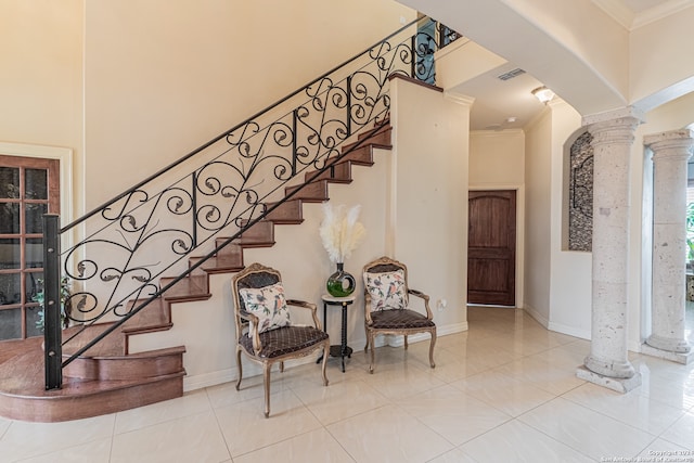 staircase featuring ornamental molding, ornate columns, and light tile floors