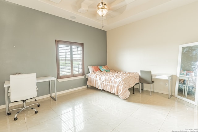 tiled bedroom with a raised ceiling and ceiling fan