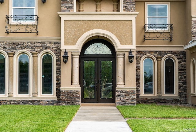 view of exterior entry featuring french doors and a yard