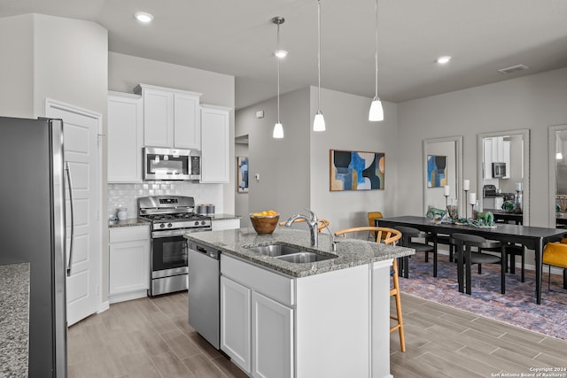 kitchen featuring stainless steel appliances, an island with sink, sink, and white cabinets