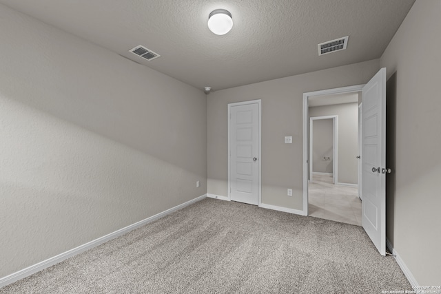 unfurnished bedroom with light colored carpet and a textured ceiling