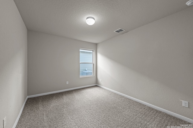 carpeted empty room featuring a textured ceiling