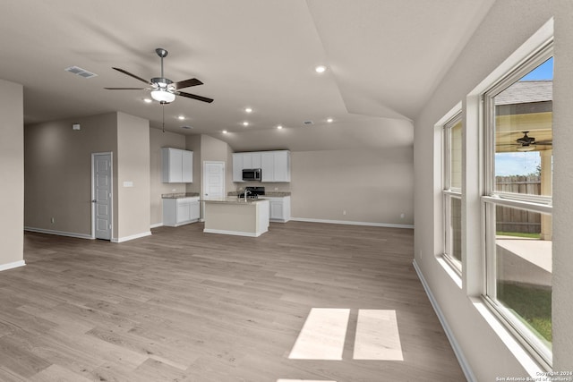 unfurnished living room with ceiling fan, vaulted ceiling, and a healthy amount of sunlight