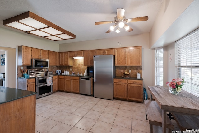 kitchen with appliances with stainless steel finishes, backsplash, light tile patterned floors, and ceiling fan